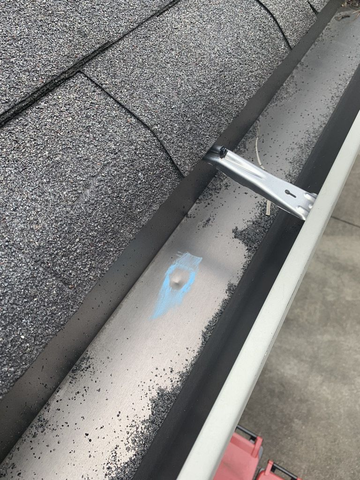 A close-up of a gutter that has sustained hail damage during a storm.