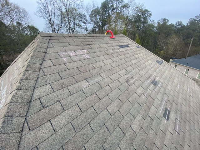 A roof with damaged shingles being inspected by the experts from Whitaker Roofing.
